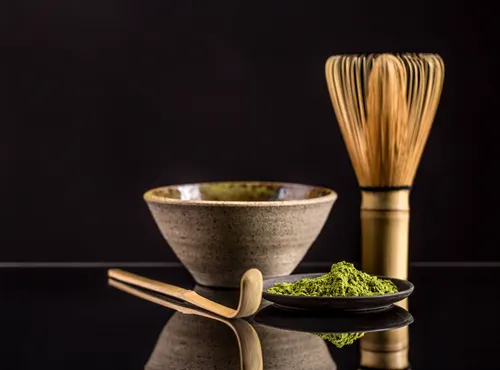 Studio still life of chawan, chasen and matcha on dark reflective surface