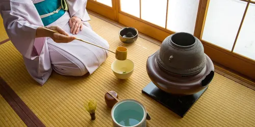 Tea master kneeling before a traditional Japanese iron kettle (kama)
